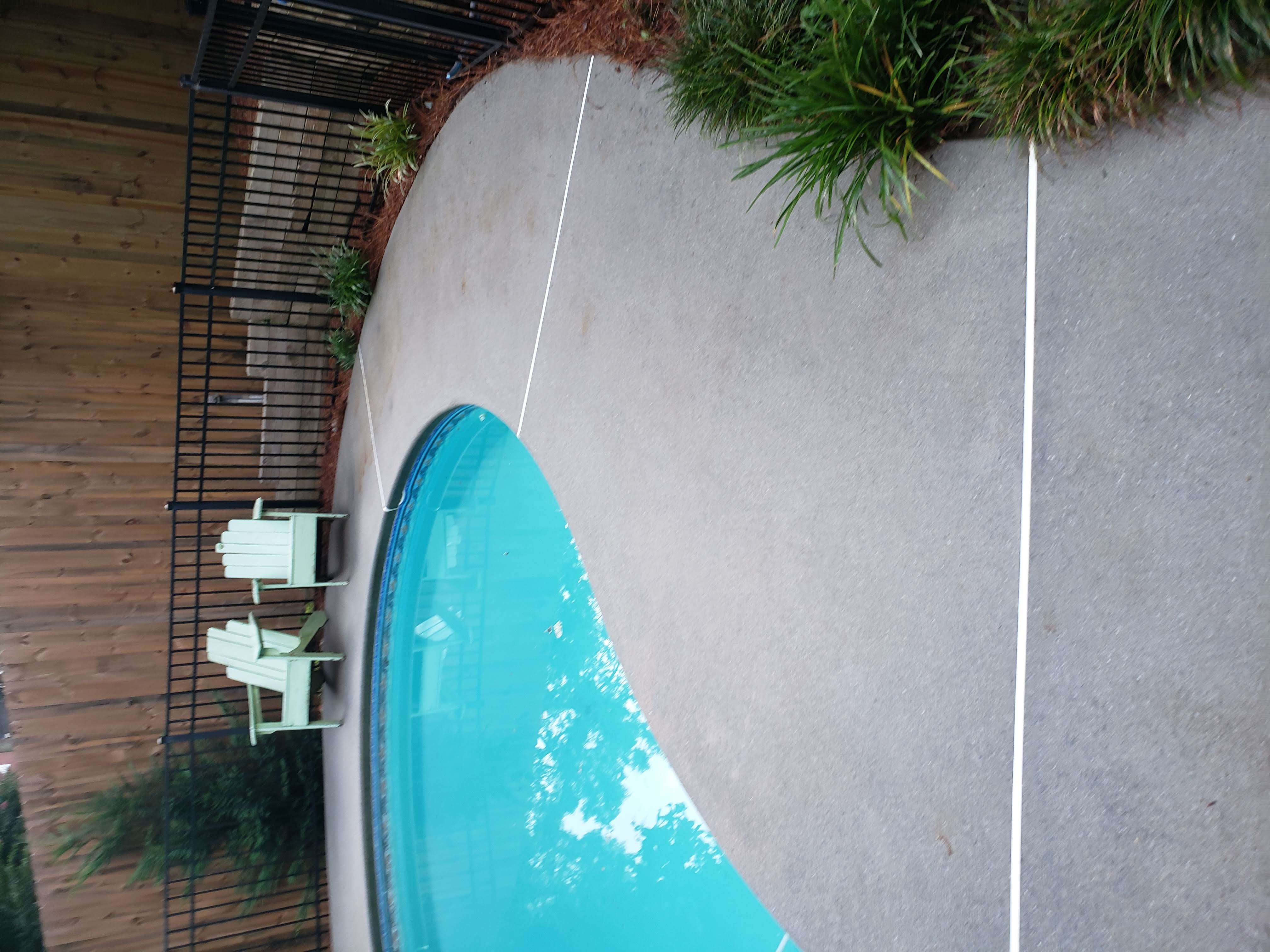 The image shows a recently cleaned pool deck by Reeves Exterior Cleaning Services. The pool deck was professionally cleaned using  professional equipment and supplies.